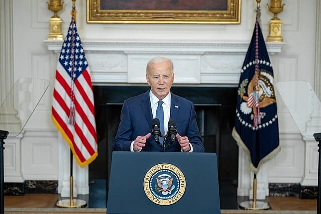 Biden standing before a podium at the White House and speaking.